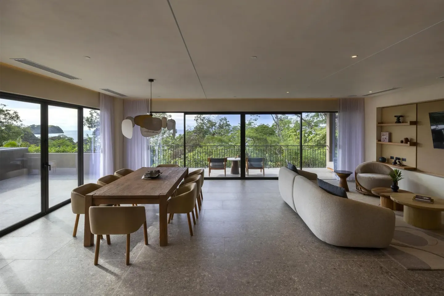 Open resort suite lounge and dining room with balcony at Waldorf Astoria Costa Rica Punta Cacique.