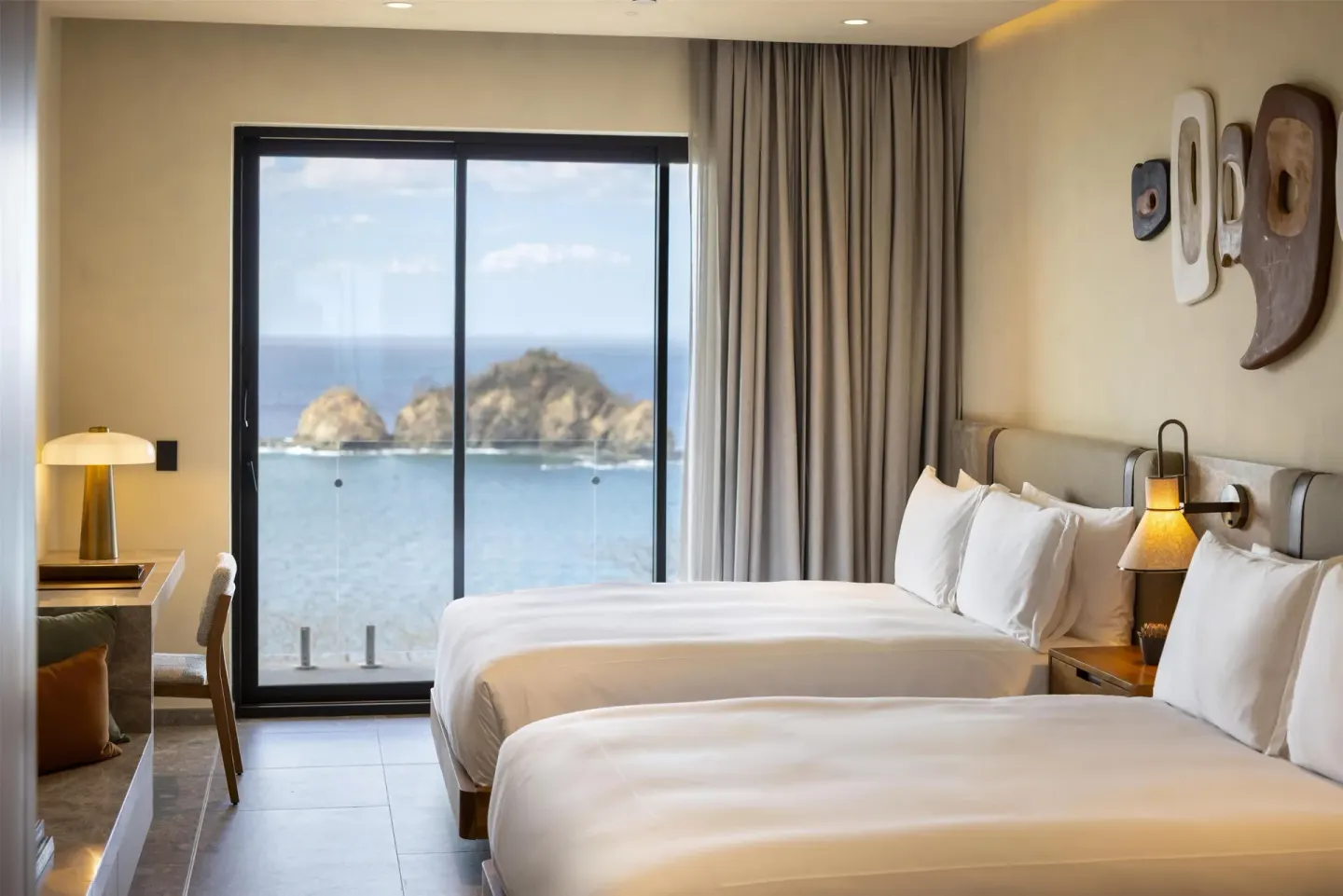 Two beds beside a large ocean-view window at Waldorf Astoria Costa Rica Punta Cacique.
