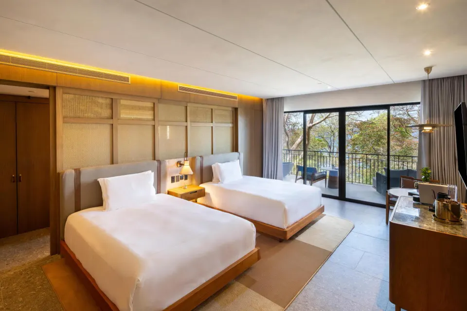 Bahia View two-queen room with balcony seating and trees outside at Waldorf Astoria Costa Rica Punta Cacique.