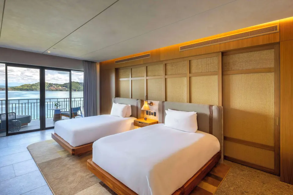 Two queen beds and a balcony overlooking the bay at Waldorf Astoria Costa Rica Punta Cacique.