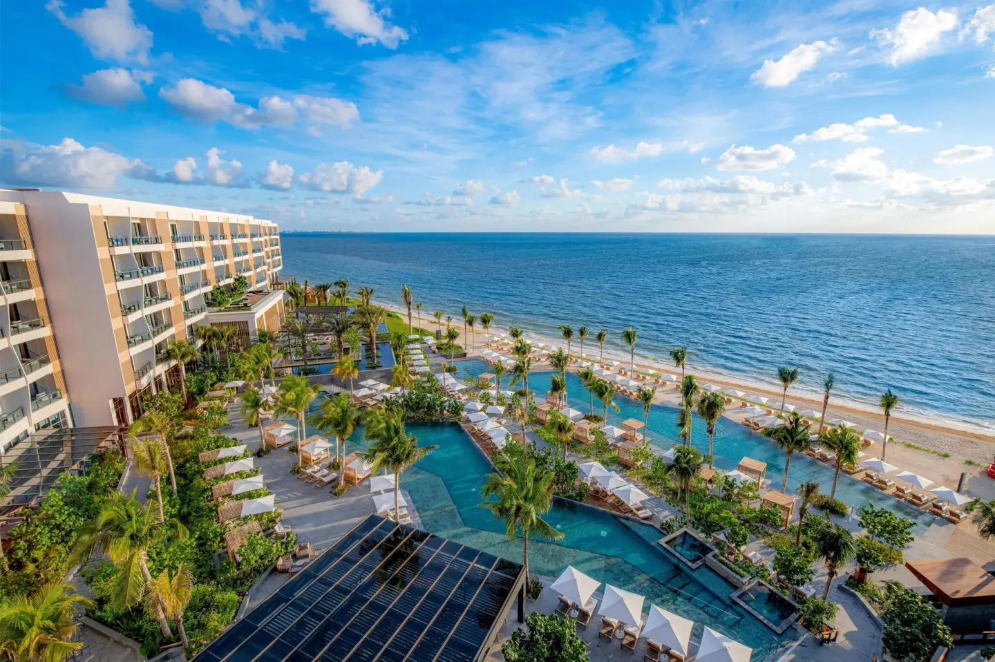 Aerial view of pools, palms, beach, and ocean at Waldorf Astoria Riviera Maya.