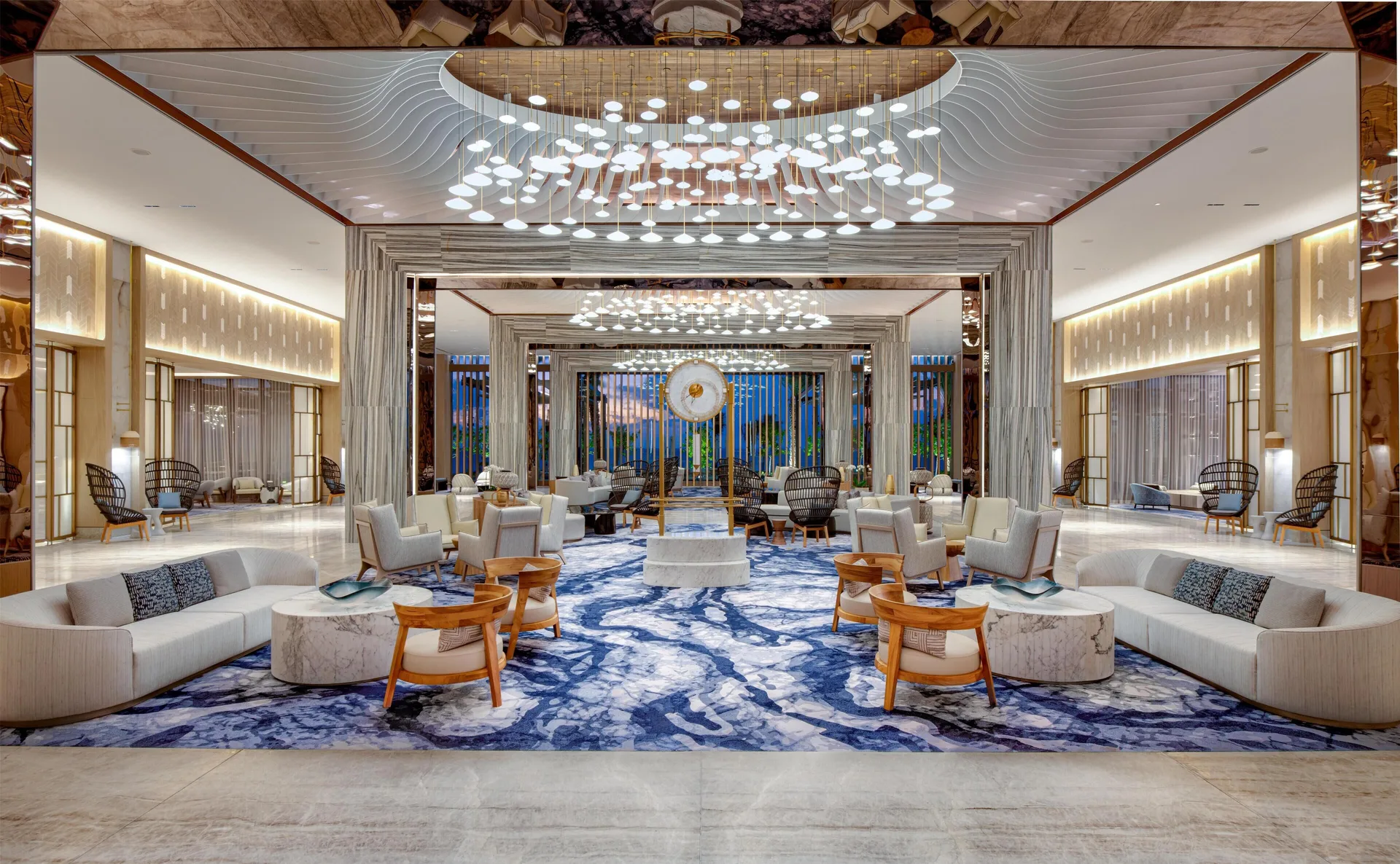 Grand lobby lounge with blue patterned rug and chandeliers at Waldorf Astoria Riviera Maya.