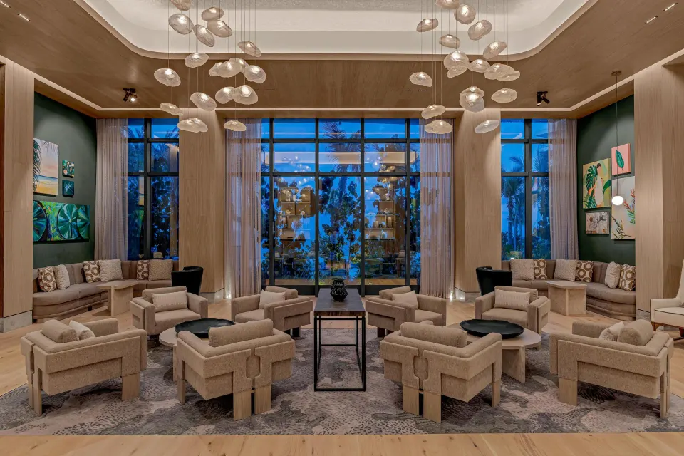 Seating lounge with tall windows and hanging glass lights at Waldorf Astoria Riviera Maya.