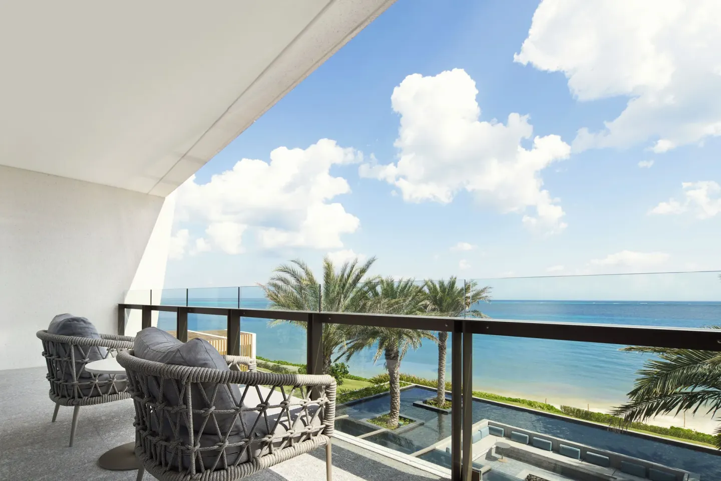 Ocean-view balcony with cushioned chairs at Waldorf Astoria Riviera Maya.
