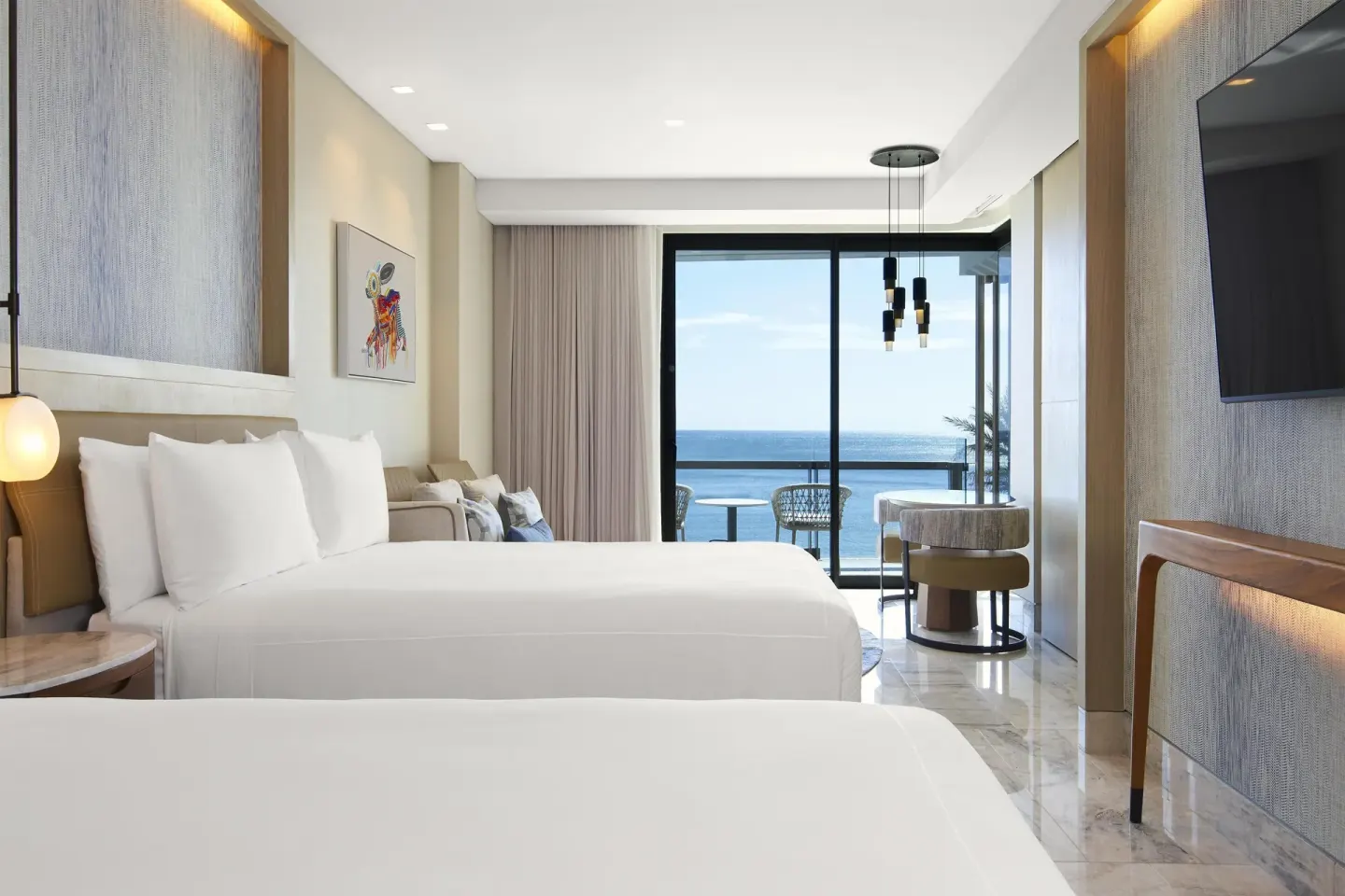 Guest room with two beds, sitting area, and ocean-facing balcony at Waldorf Astoria Riviera Maya.