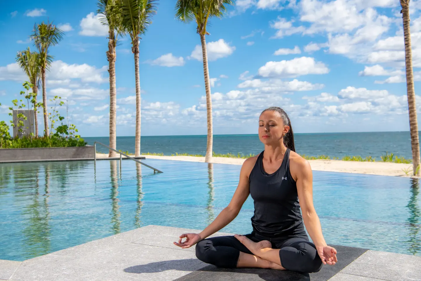 Guest meditates beside the oceanfront pool at Waldorf Astoria Riviera Maya.