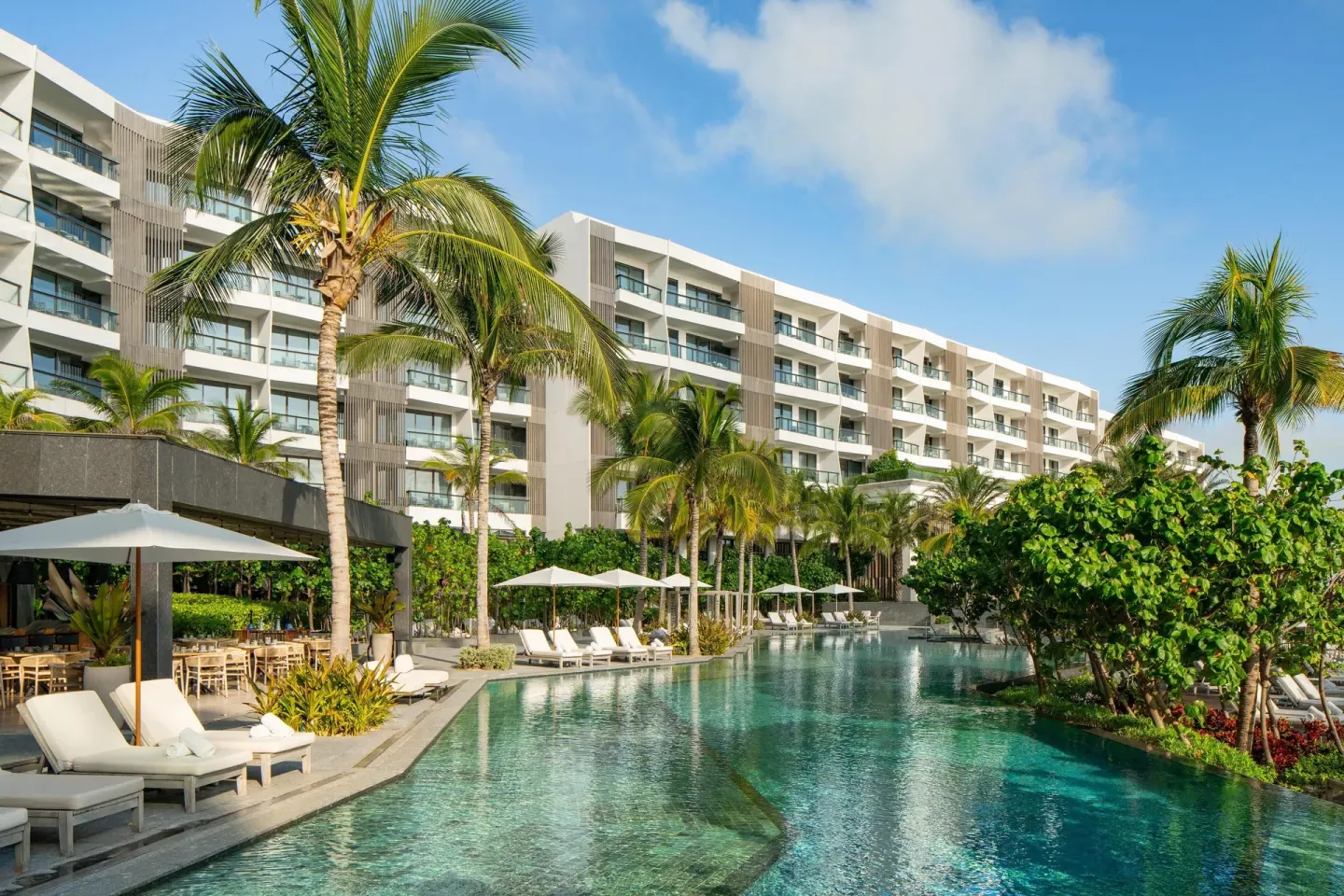 Palm-lined resort pool and guest room balconies at Waldorf Astoria Riviera Maya.