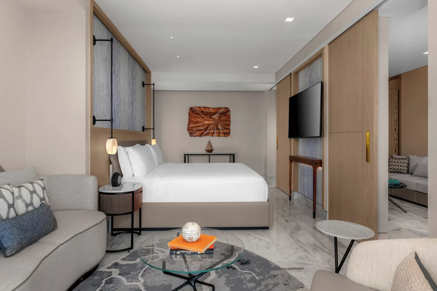 King bed suite with sofa seating and wall-mounted TV at Waldorf Astoria Riviera Maya.