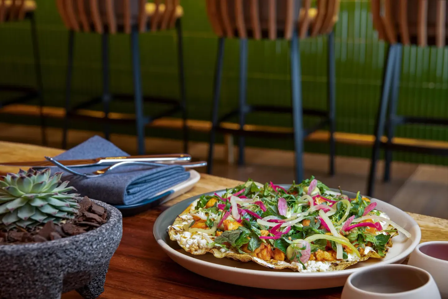Mexican dish with greens beside a stone bowl at Waldorf Astoria Riviera Maya.