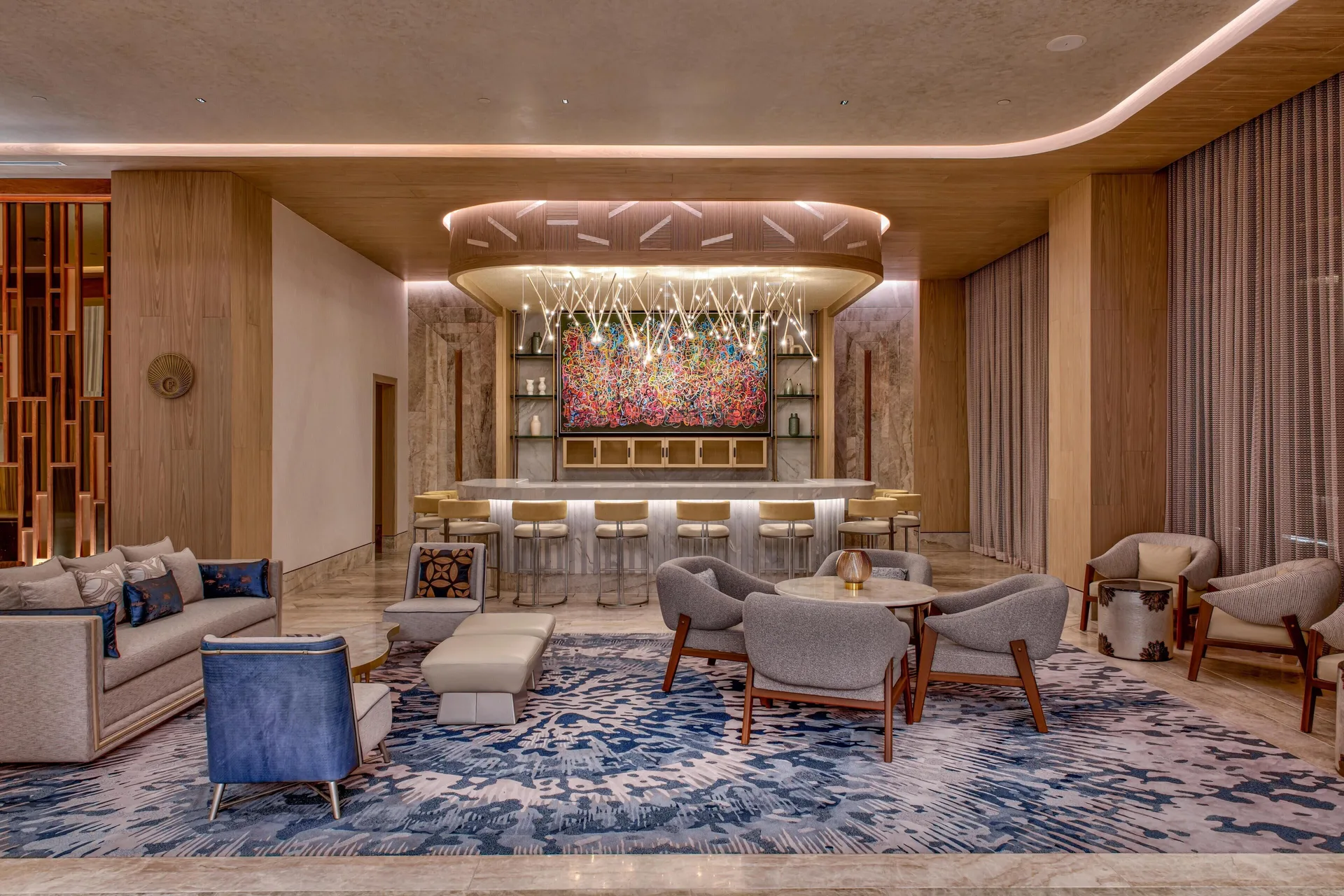 Lobby lounge bar with sofas, chairs and a colorful artwork at Waldorf Astoria Riviera Maya.