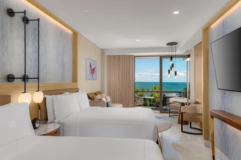 Oceanfront two-queen guest room with balcony view at Waldorf Astoria Riviera Maya.
