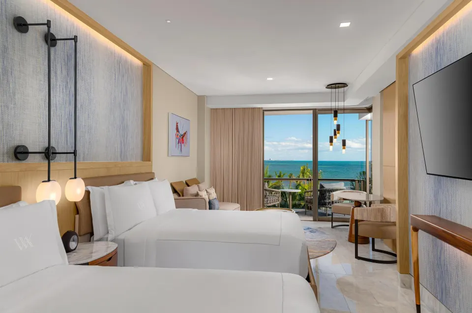 Oceanfront two-queen guest room with balcony view at Waldorf Astoria Riviera Maya.