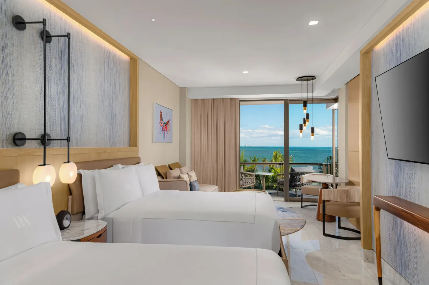 Two-queen oceanfront room with seating and TV at Waldorf Astoria Riviera Maya.