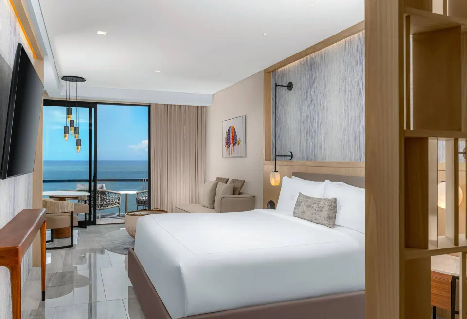 Deluxe Ocean Front king bed beside a balcony view at Waldorf Astoria Riviera Maya.