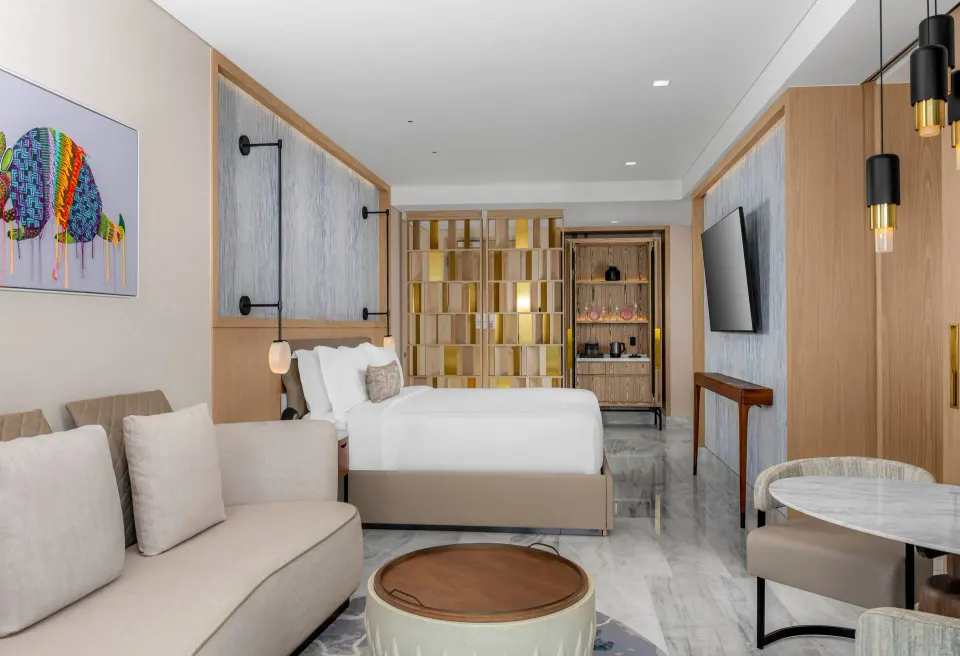 Deluxe Ocean Front guestroom with bed, sofa, table, and TV at Waldorf Astoria Riviera Maya.