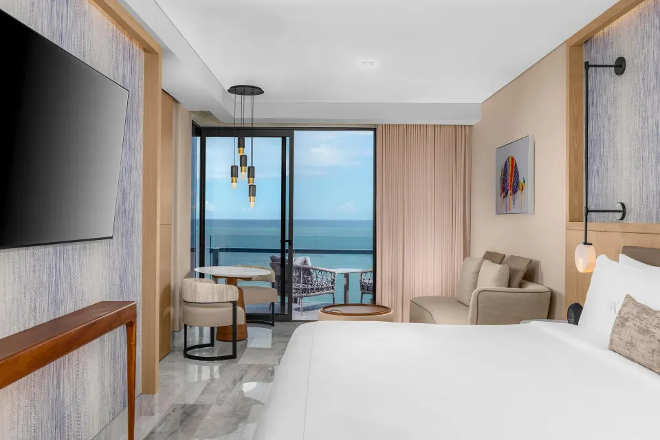 Deluxe Ocean View king room with bed, balcony doors, and ocean beyond at Waldorf Astoria Riviera Maya.