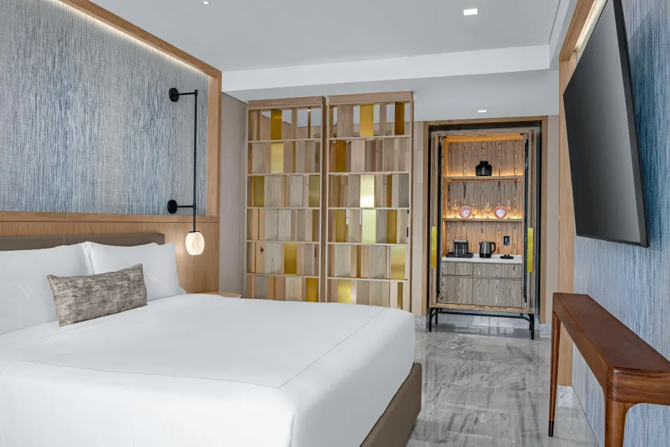 Deluxe Ocean View king bed with partition shelving and refreshment cabinet at Waldorf Astoria Riviera Maya.