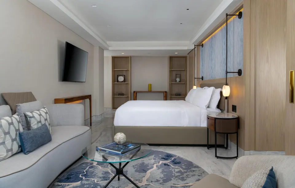 Presidential Suite king bedroom with sofa and wall-mounted TV at Waldorf Astoria Riviera Maya.