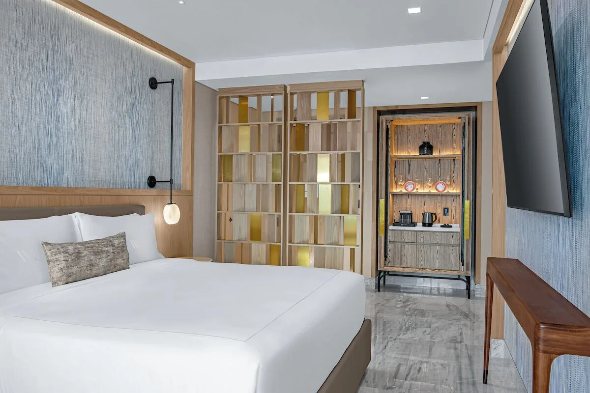 Accessible room with king bed, wall TV, and refreshment cabinet at Waldorf Astoria Riviera Maya.