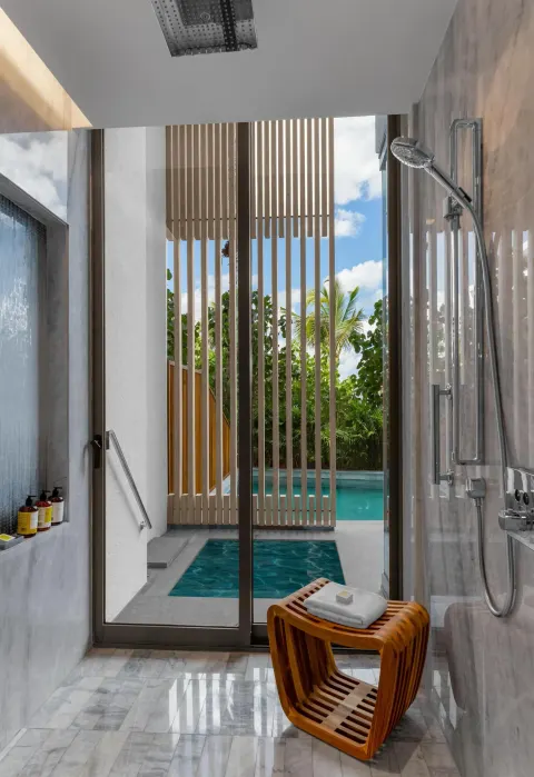 Guest room shower with glass doors to swim-up pool at Waldorf Astoria Riviera Maya.