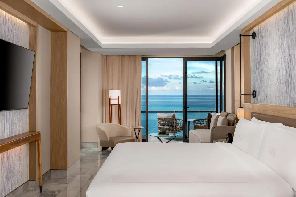 Corner ocean view suite king bed facing a balcony and sea at Waldorf Astoria Riviera Maya.