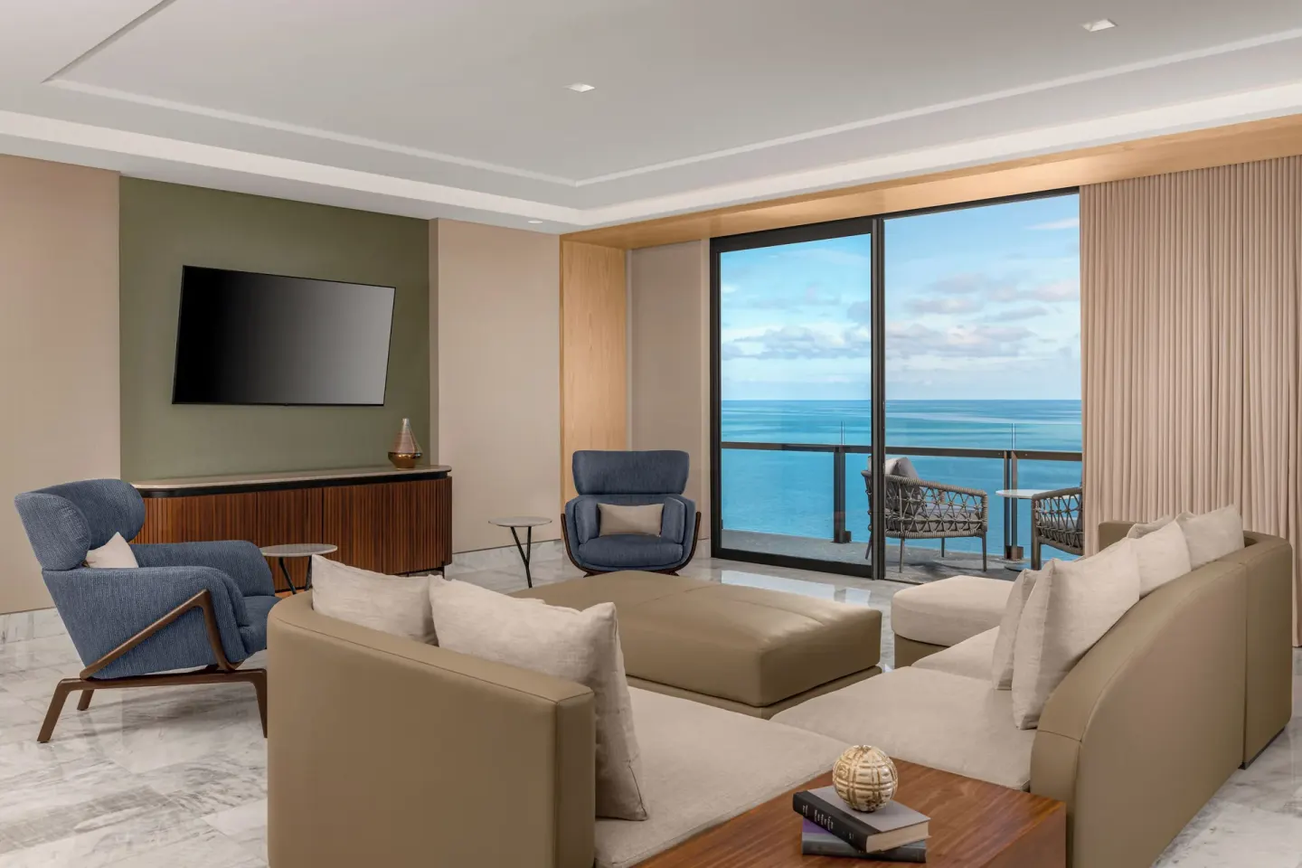 Corner ocean view suite lounge with sofas, chairs, and balcony at Waldorf Astoria Riviera Maya.