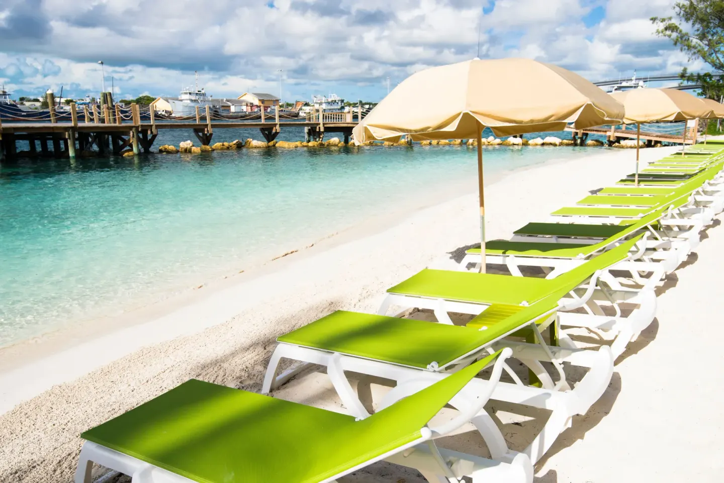 Green lounge chairs and umbrellas face the beach at Warwick Paradise Island.