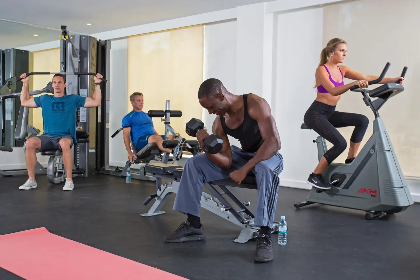 Guests using cardio and strength equipment in the fitness center at Warwick Paradise Island.