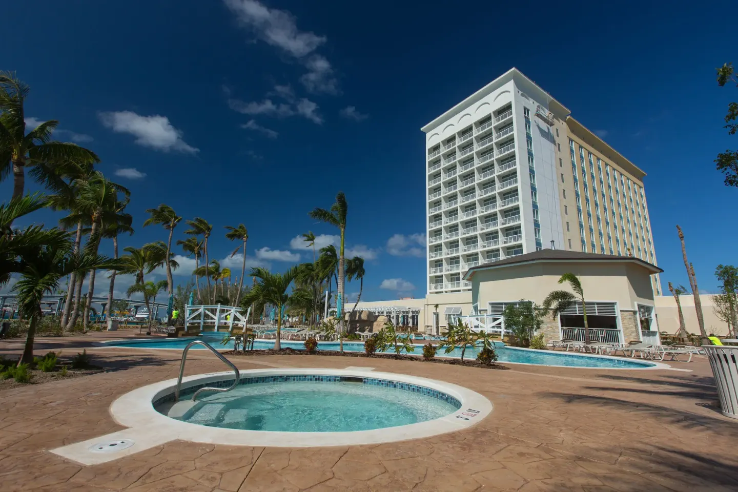 Round hot tub, pool deck and hotel tower among palms at Warwick Paradise Island.