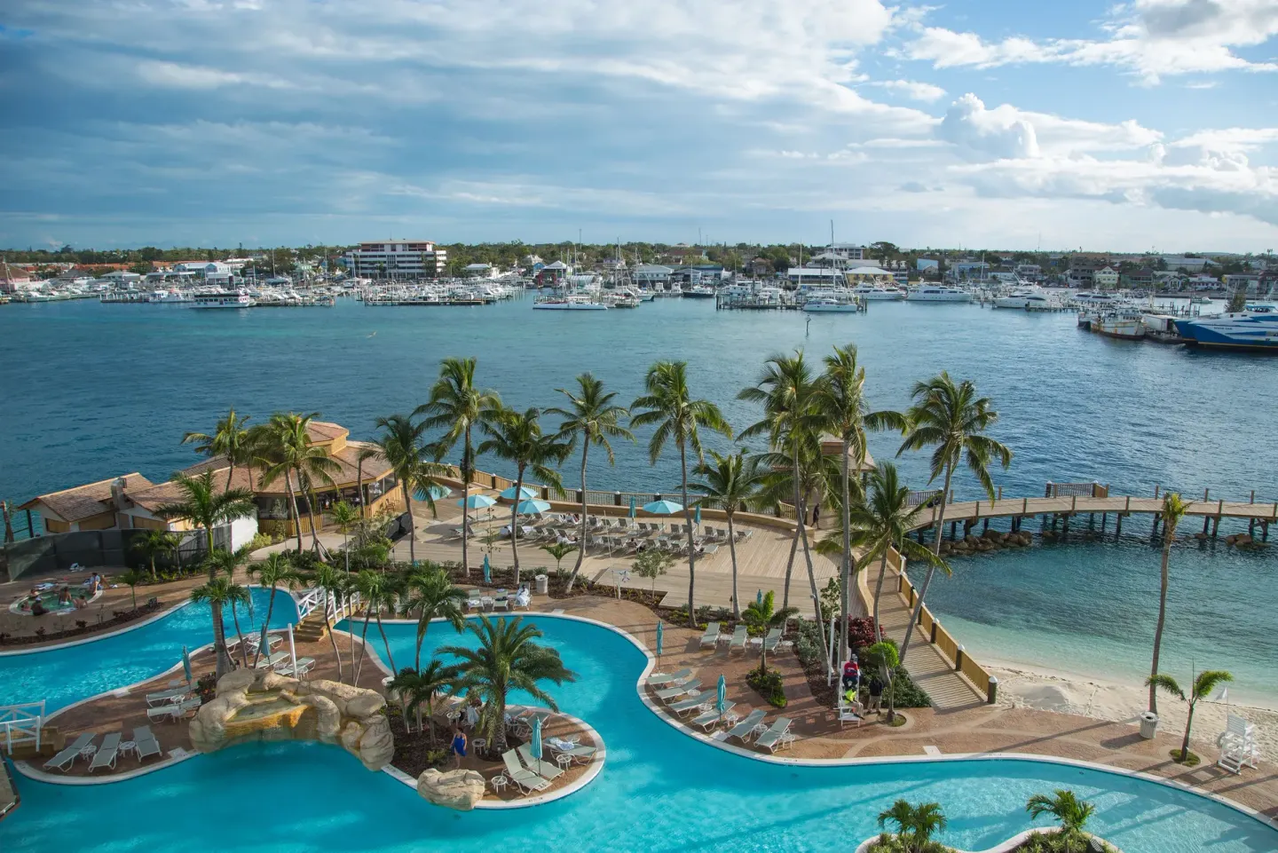 Pool deck, palm trees, beach and marina view at Warwick Paradise Island.