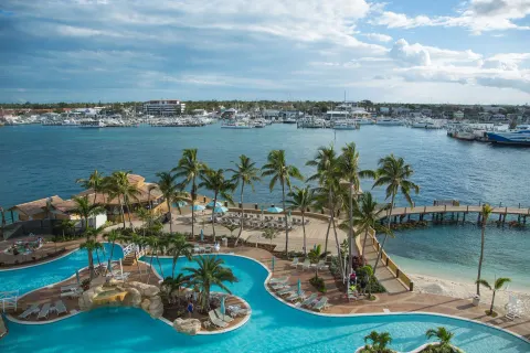Pool deck, palm trees, beach and marina view at Warwick Paradise Island.