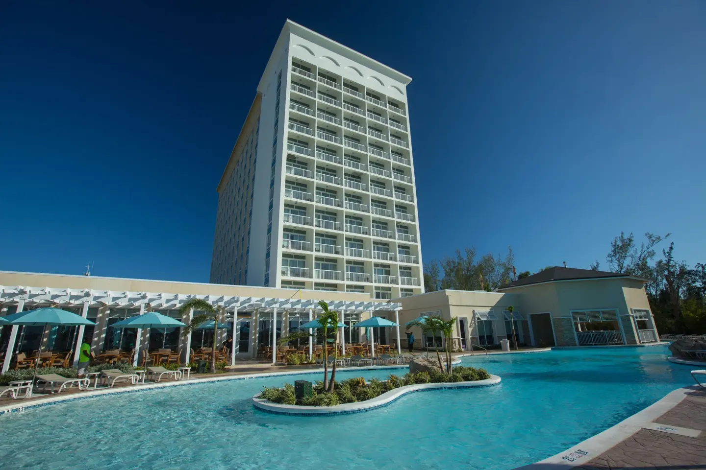Swimming pool with terrace seating and the hotel tower at Warwick Paradise Island.