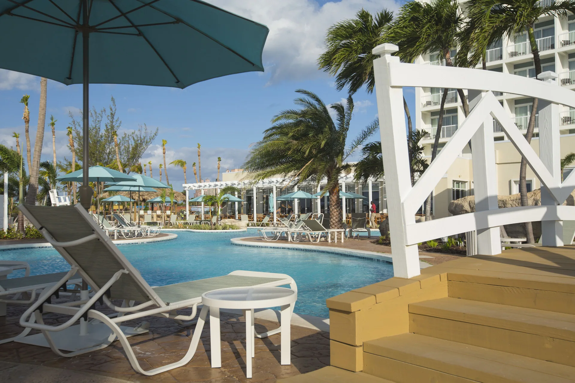 Poolside loungers, umbrellas and palms beside the building at Warwick Paradise Island.
