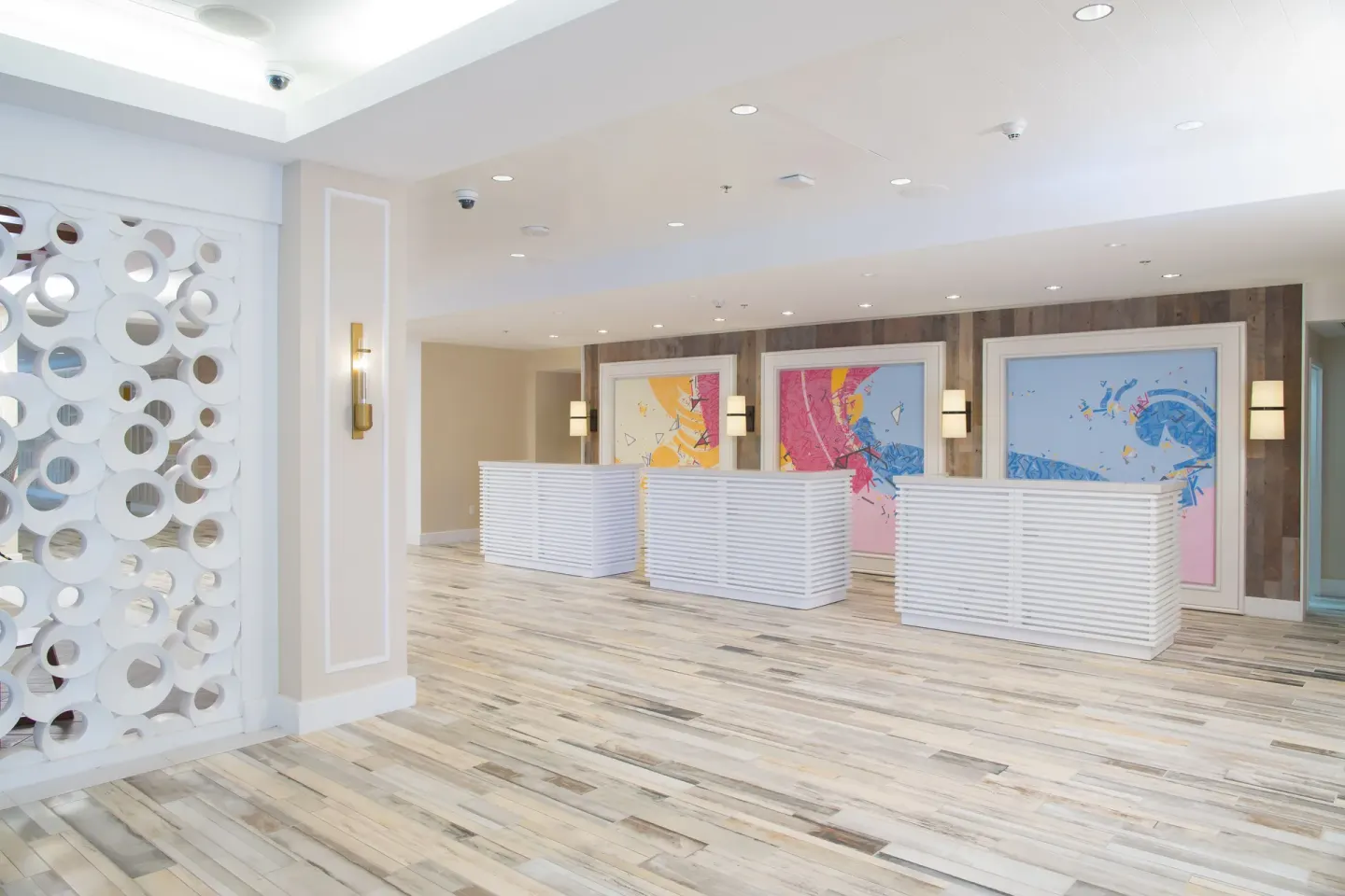 Bright reception lobby with white desks and colorful art at Warwick Paradise Island.