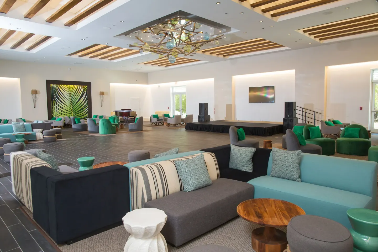 A spacious lounge with sofas, green chairs, and a stage at Warwick Paradise Island.