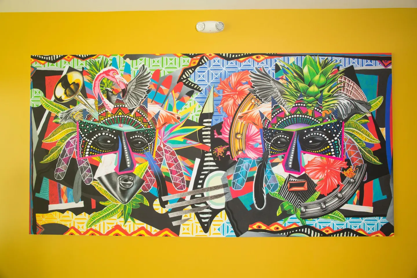 Colorful tropical mural with masks and birds on a yellow wall at Warwick Paradise Island.