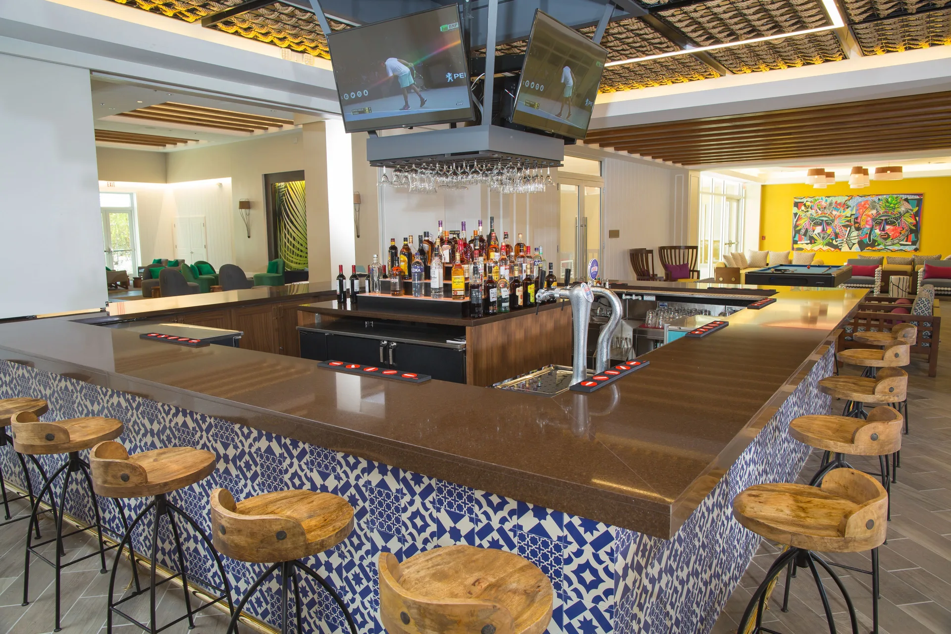 Lobby bar with patterned tile, stools, bottles, and TVs at Warwick Paradise Island.