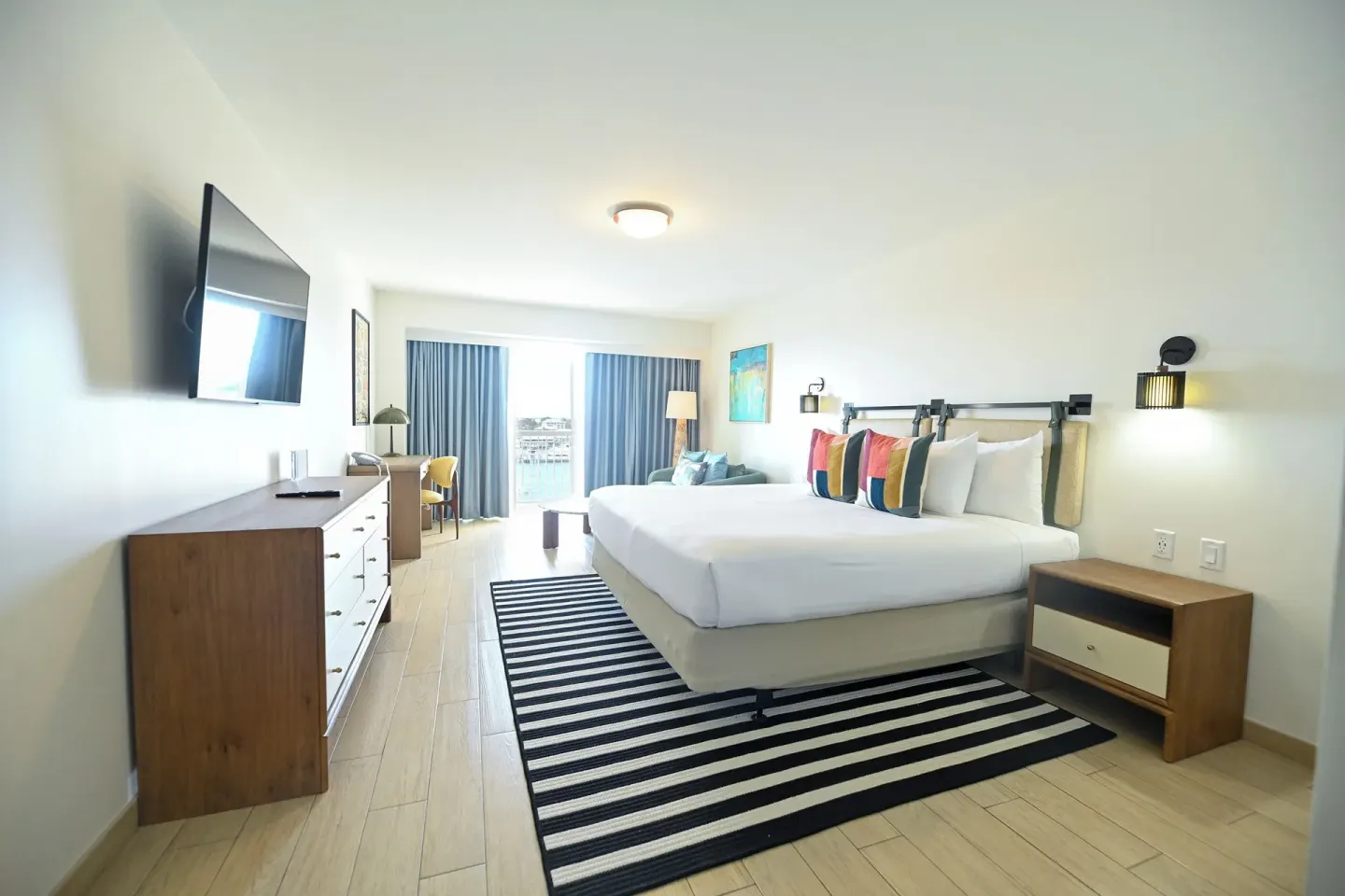 Harbour Deluxe Balcony king room with bed, TV, dresser and balcony doors at Warwick Paradise Island.