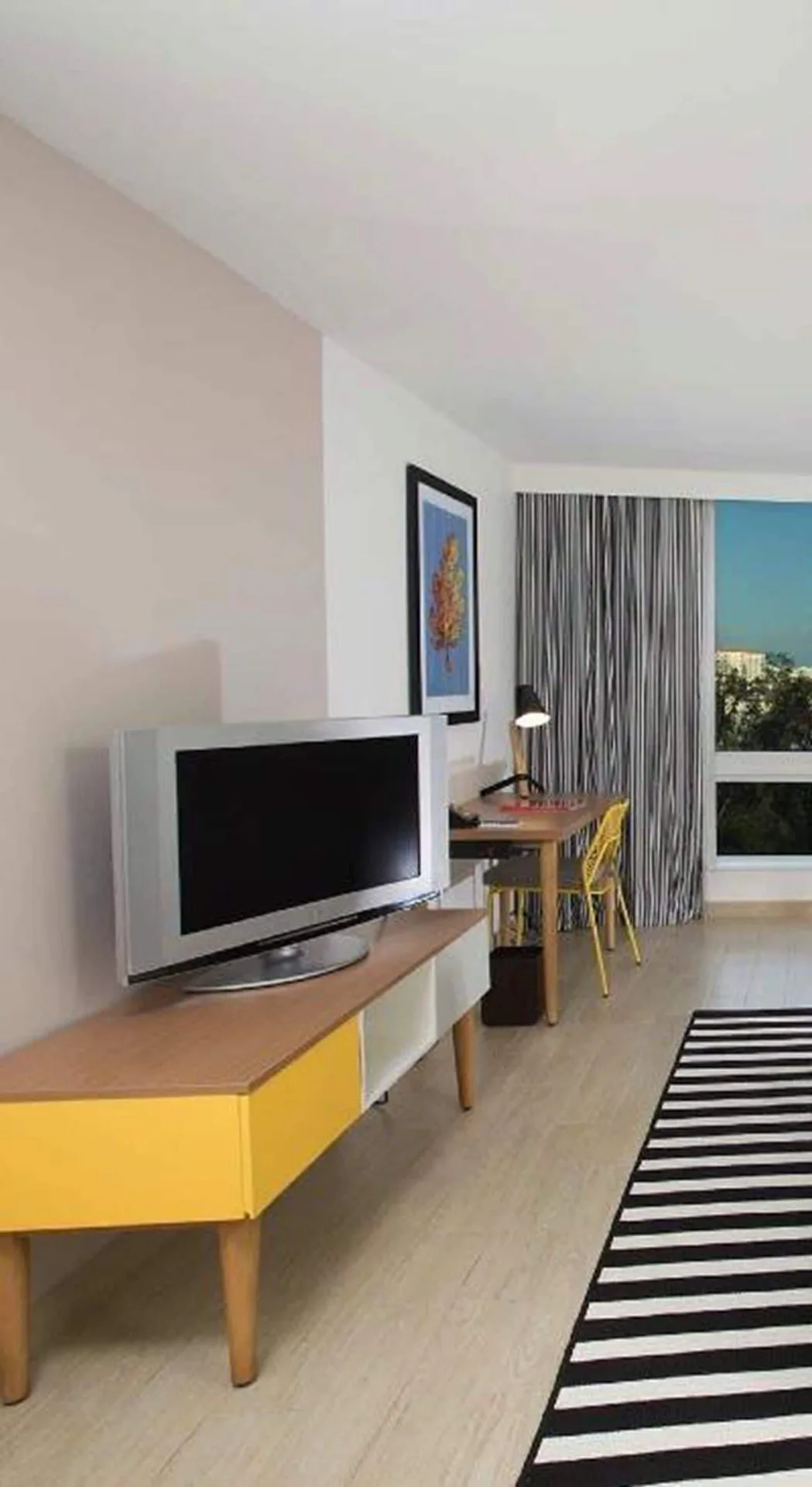 Island View guest room desk, TV, and window at Warwick Paradise Island.