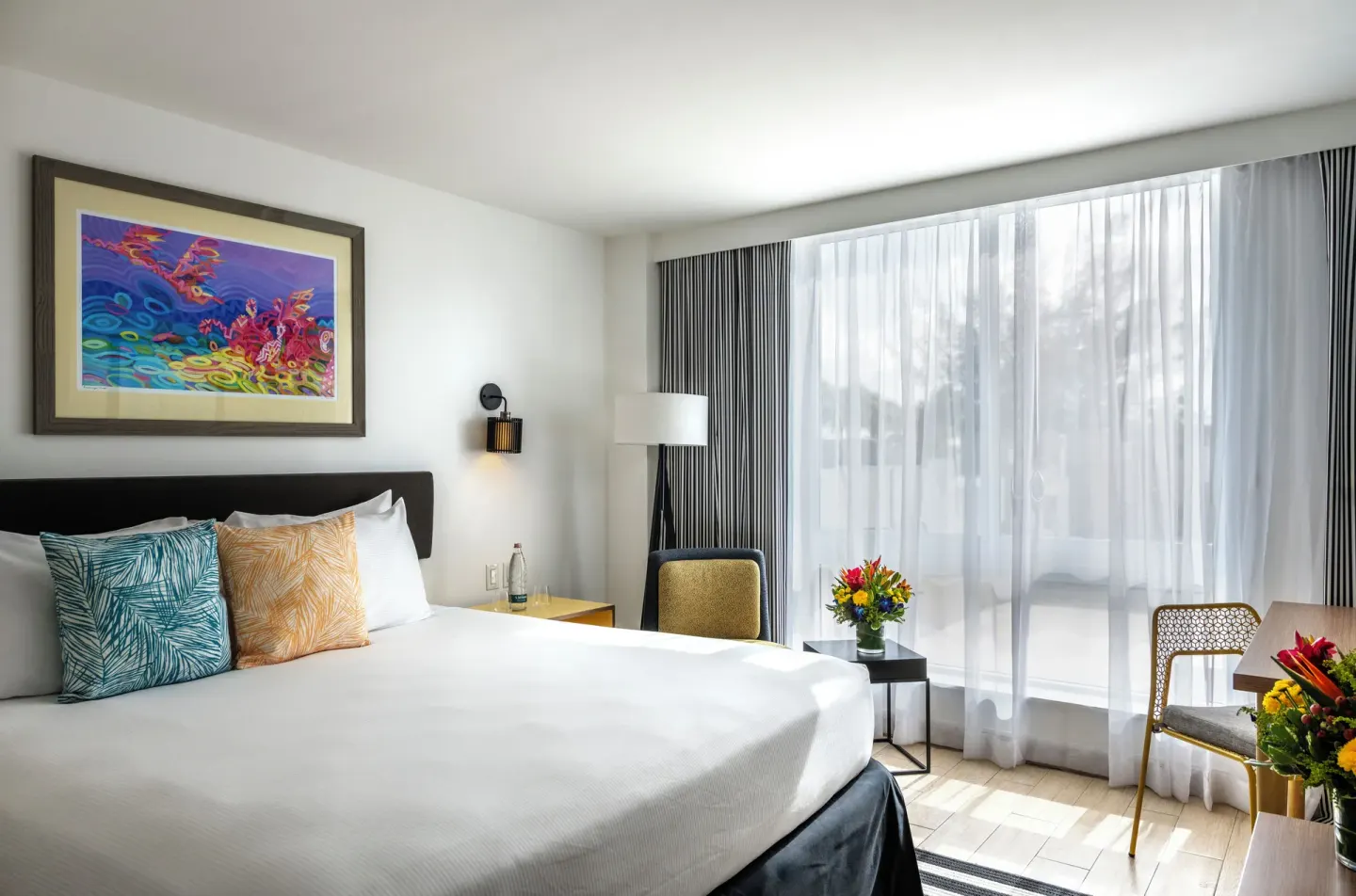 Island View King room with bed, colorful art, and sheer window curtains at Warwick Paradise Island.