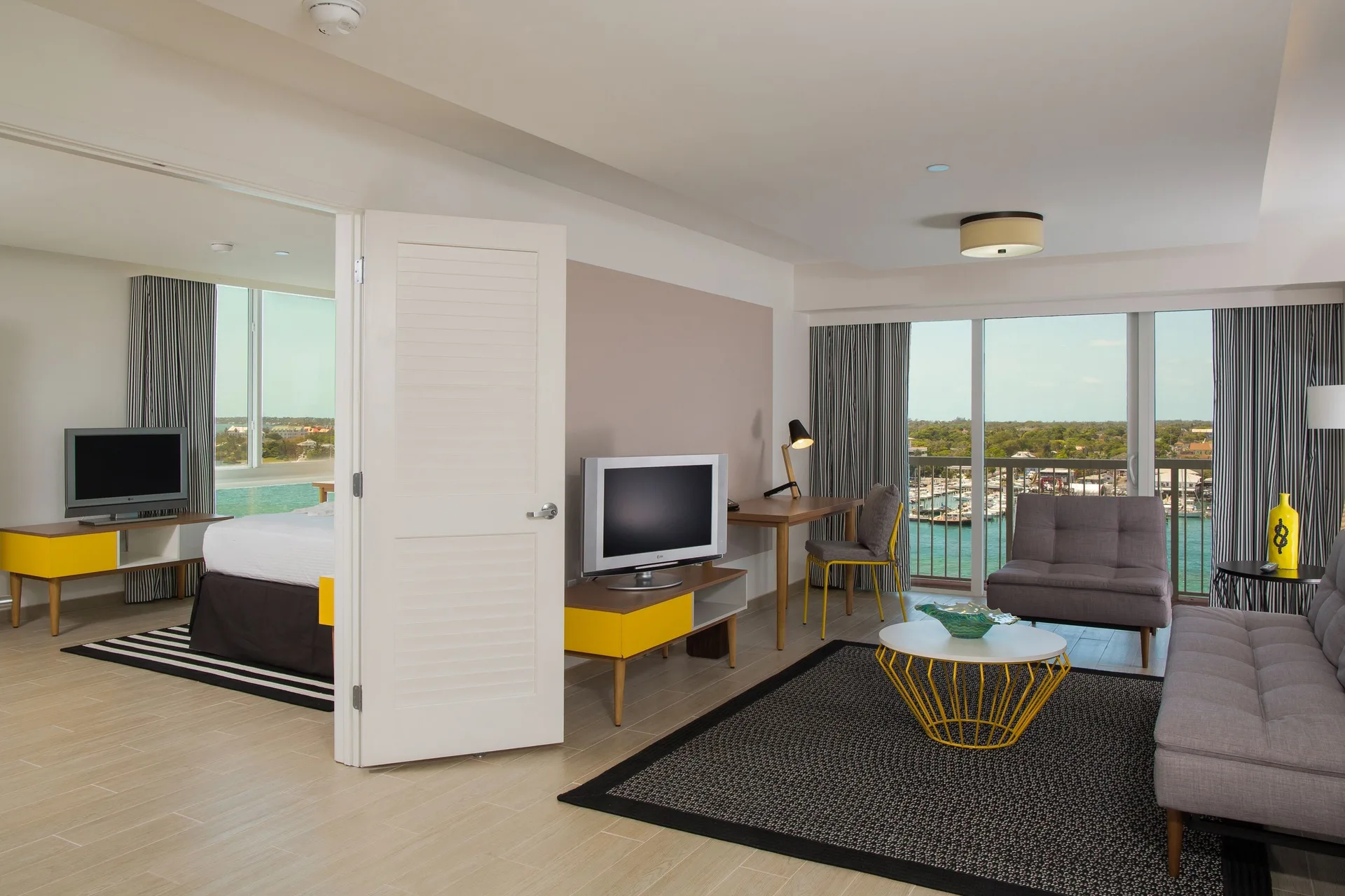 One Bedroom Harbourfront Suite living room and bed at Warwick Paradise Island with balcony harbour view.