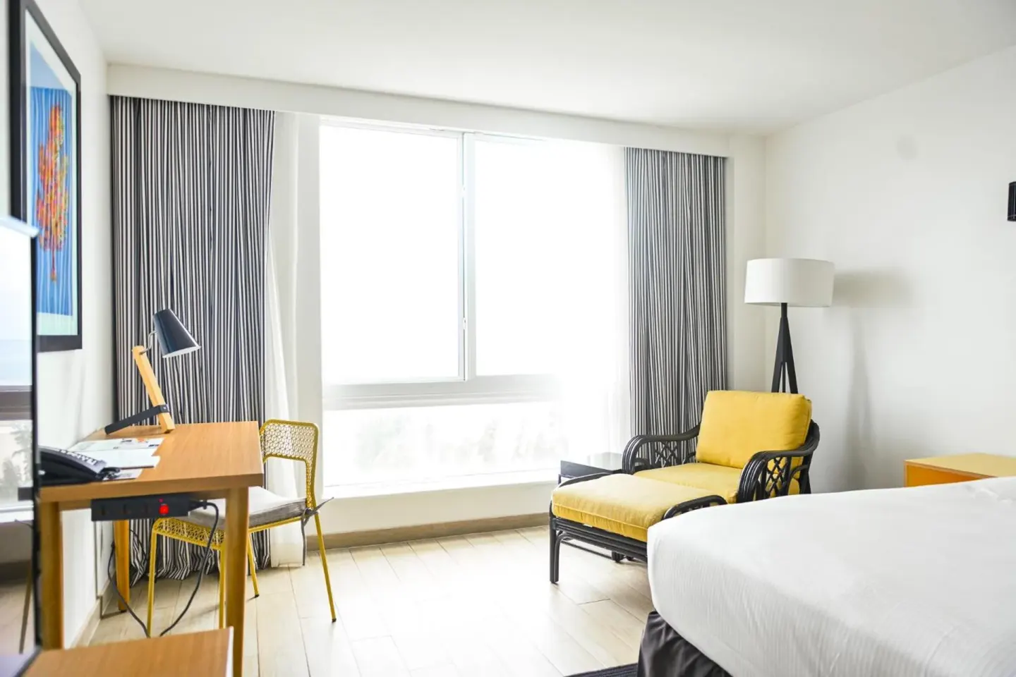 Water View room with bed, desk, yellow chair and bright window at Warwick Paradise Island.