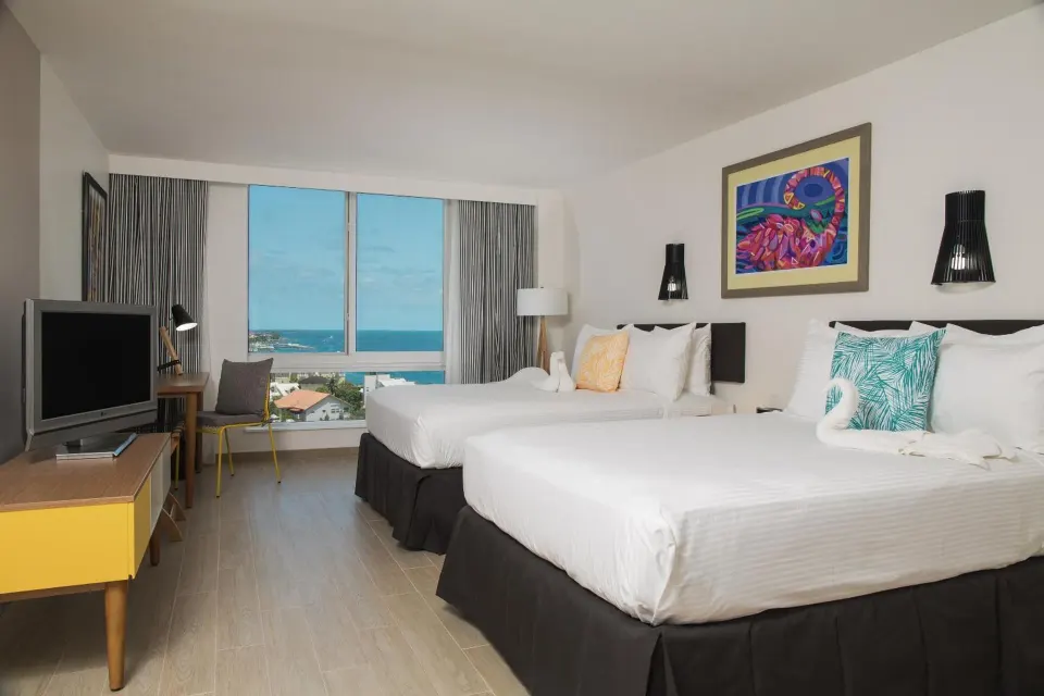Water View room with two beds, TV and ocean view windows at Warwick Paradise Island.
