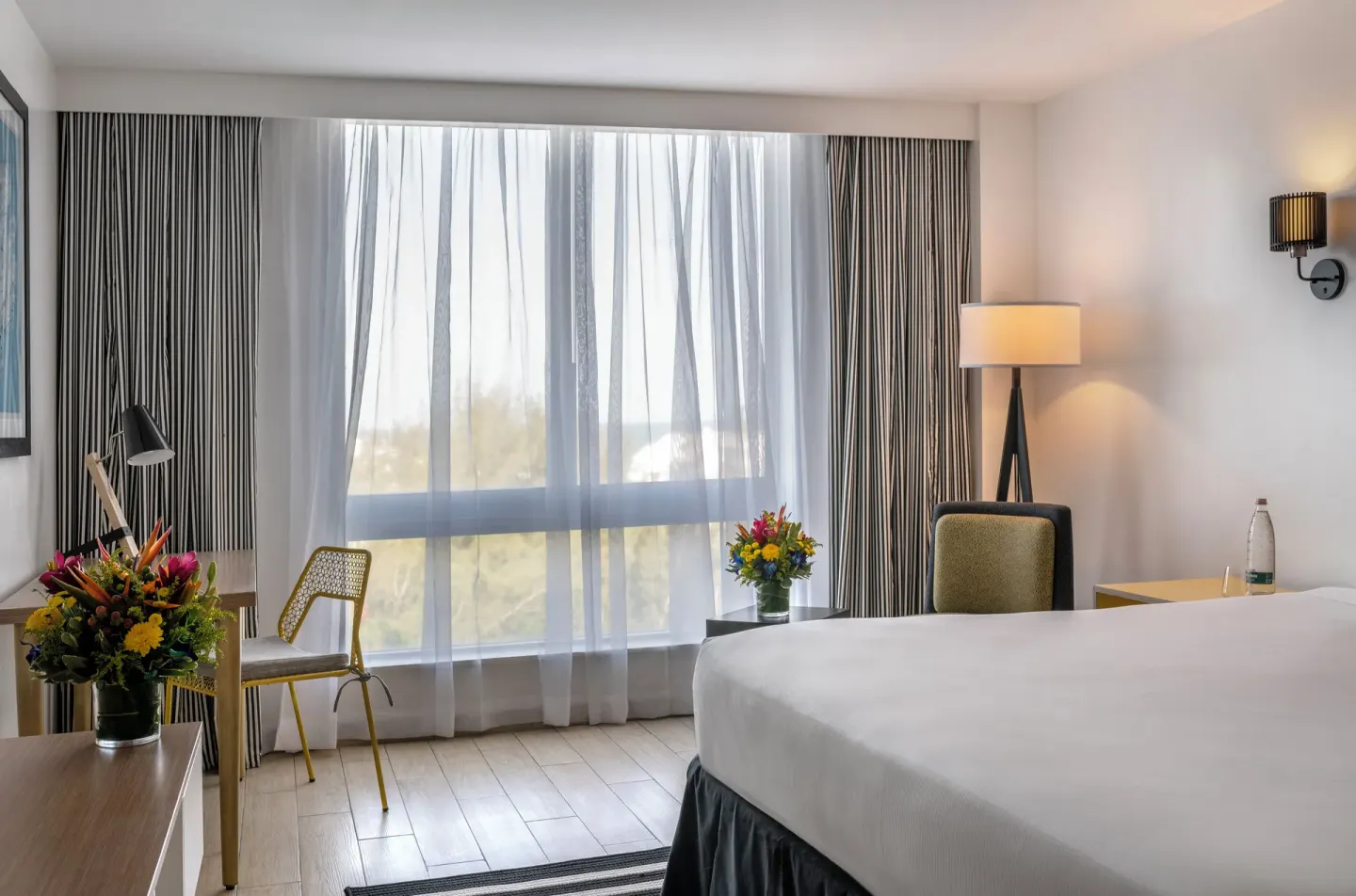 Water View king room at Warwick Paradise Island with bed, desk, seating, and large curtained window.