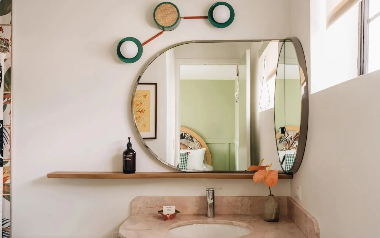 Guest bathroom sink and mirror reflect a bedroom beyond at Wayfinder Waikiki.