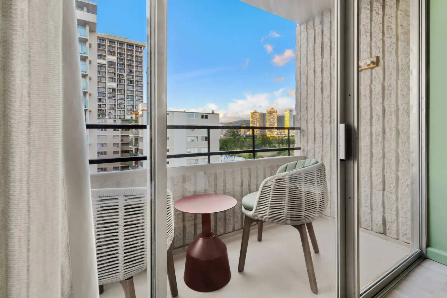 Guest room balcony with two chairs and a city view at Wayfinder Waikiki.