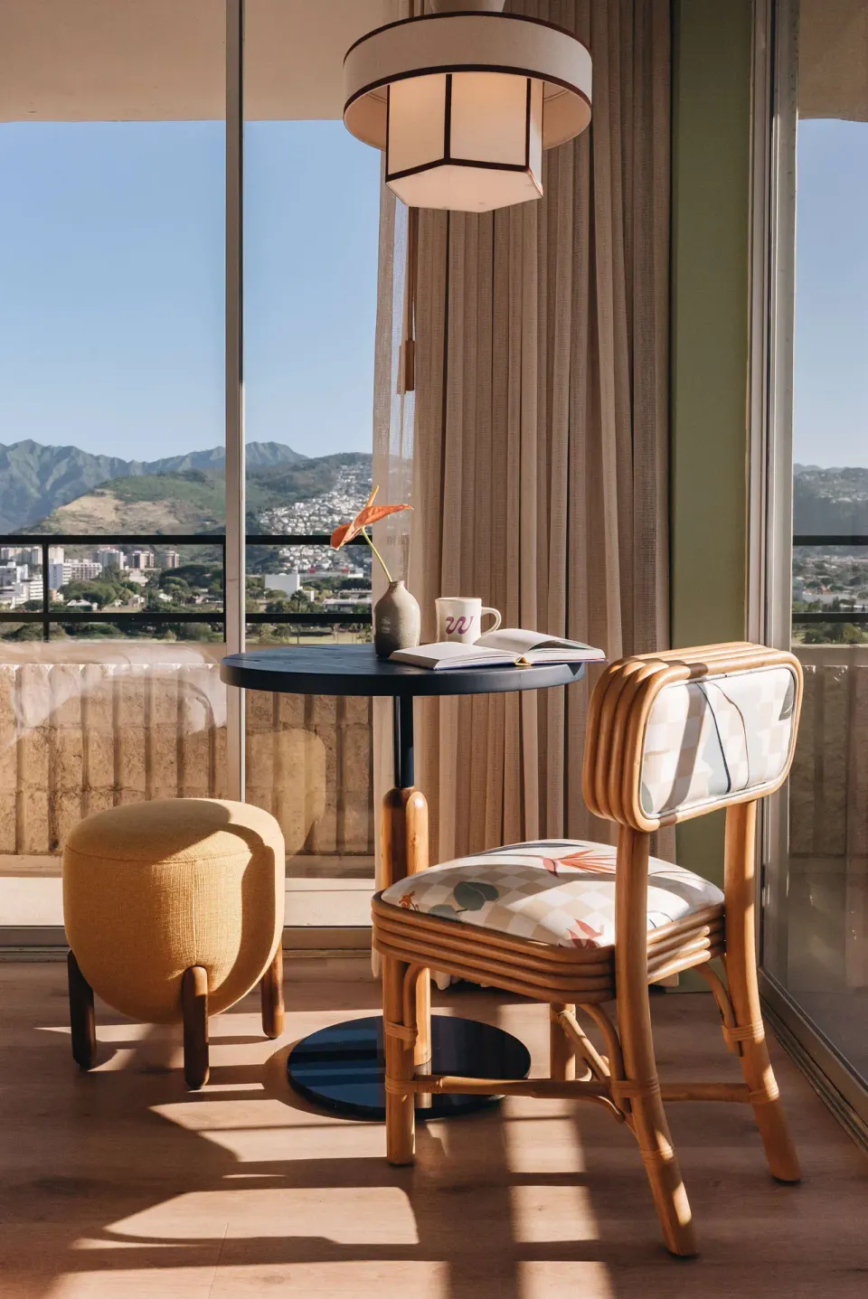 Balcony-side guest room table and chair with mountain views at Wayfinder Waikiki.
