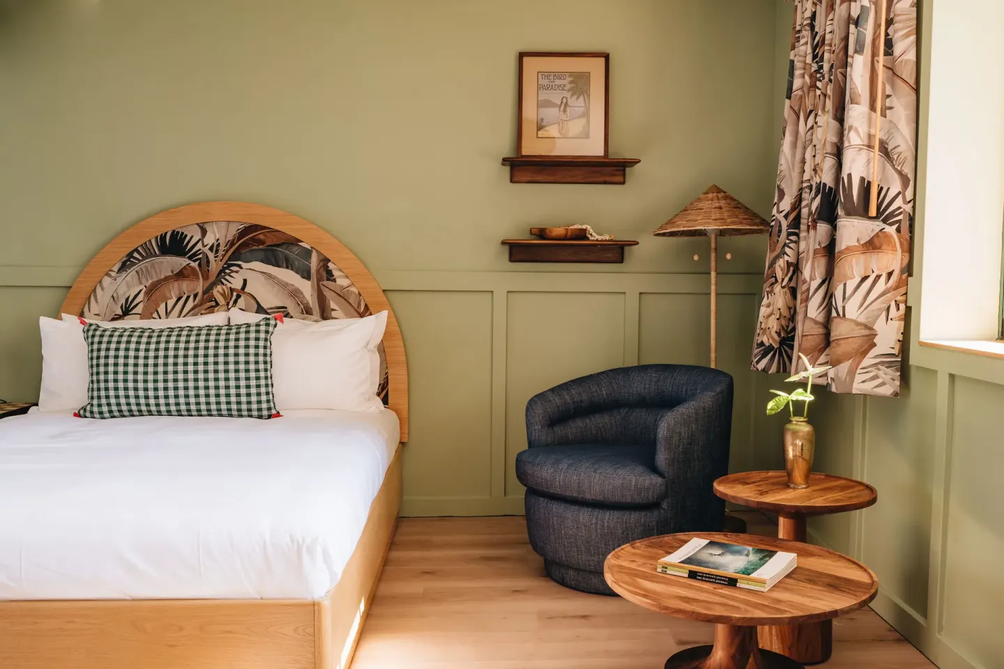 Guest room with bed, lounge chair, and round tables at Wayfinder Waikiki.