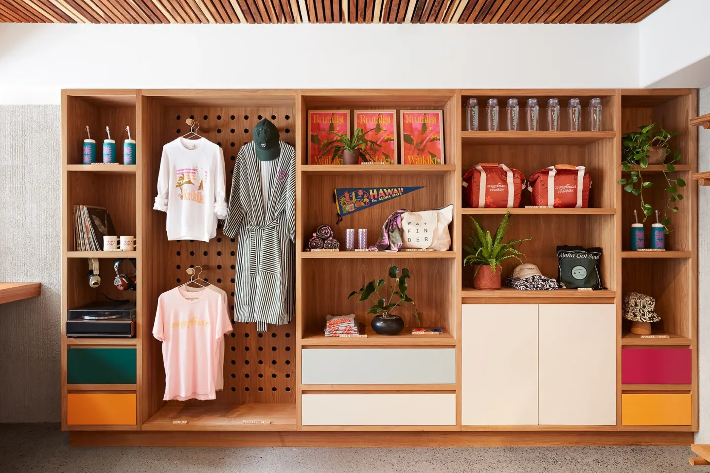 Lobby retail shelves with apparel, books, plants, and souvenirs at Wayfinder Waikiki.