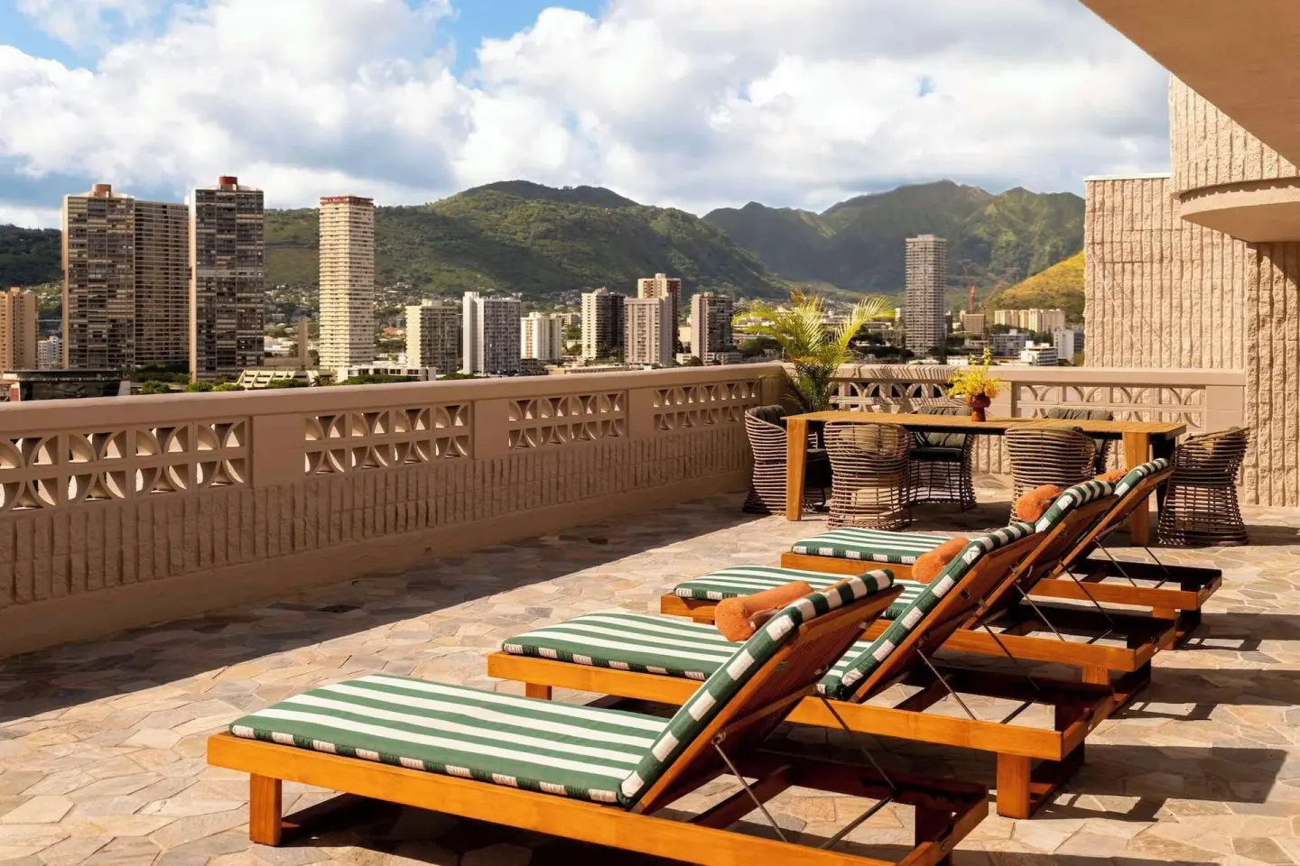 Outdoor terrace loungers with Waikiki skyline and mountains at Wayfinder Waikiki.